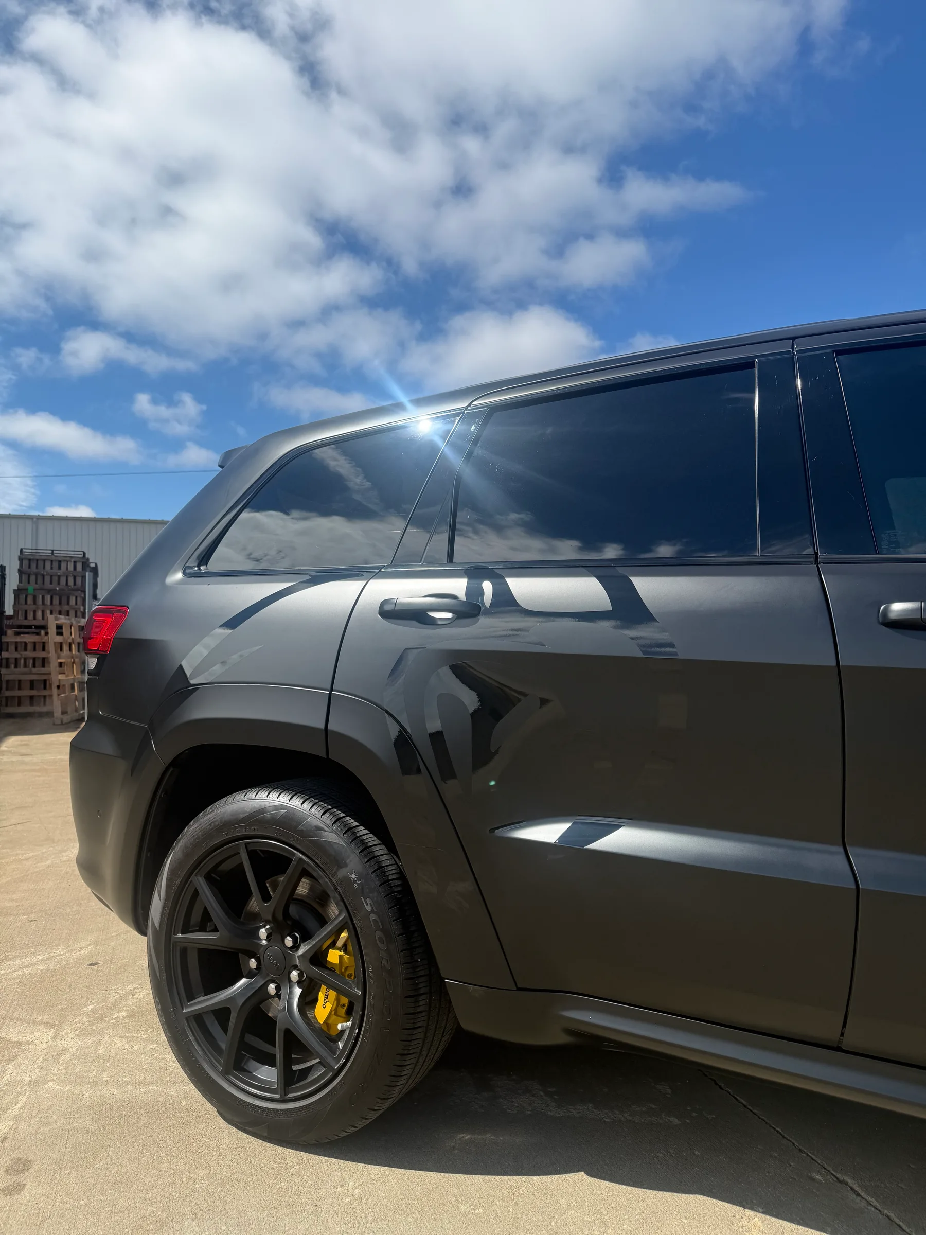 Side view of a dark gray SUV with dark window tinting and yellow brake calipers, parked outdoors.
