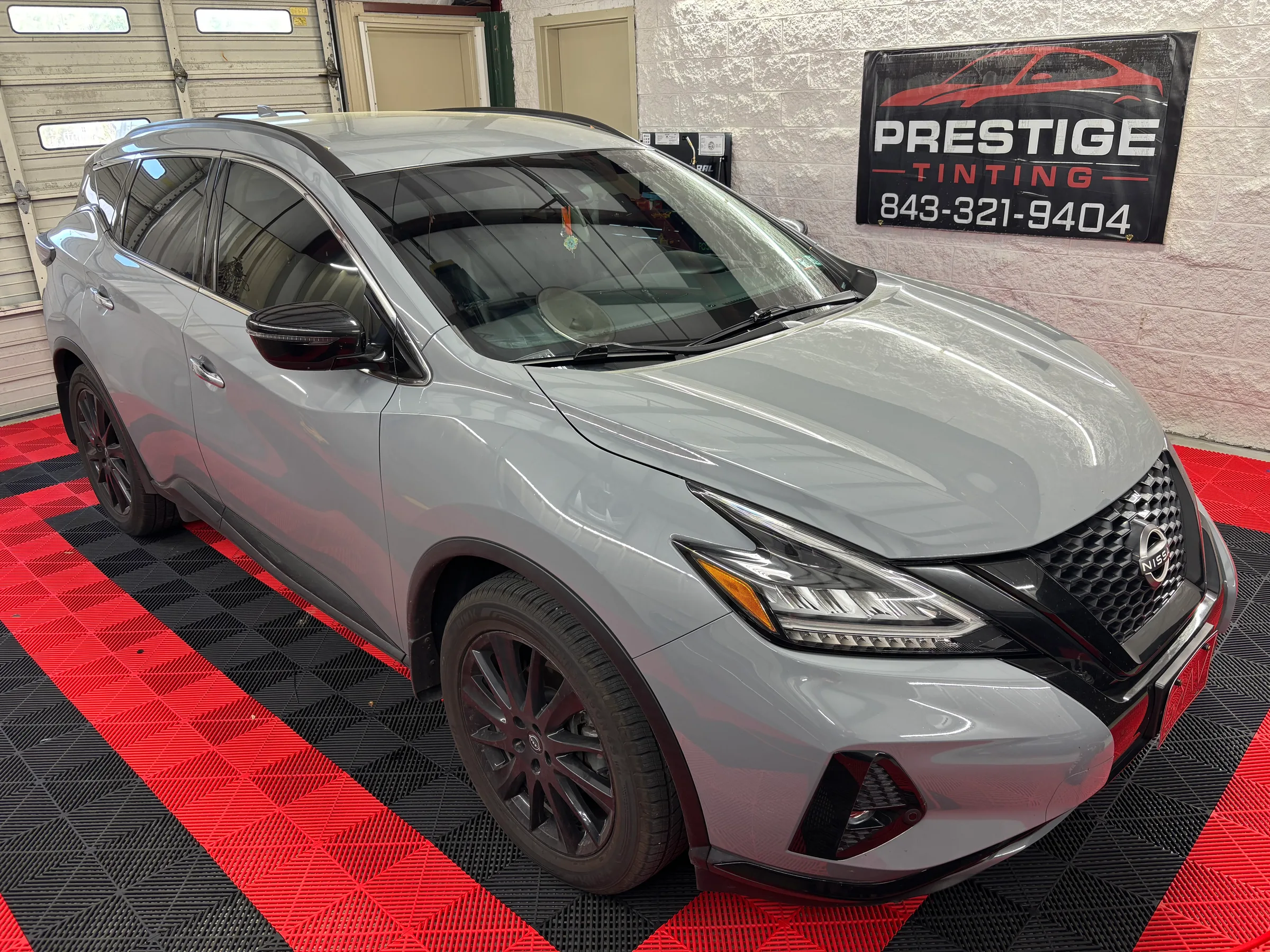 A silver Nissan Murano with dark window tint displayed in the Prestige Tinting showroom in Conway, SC.