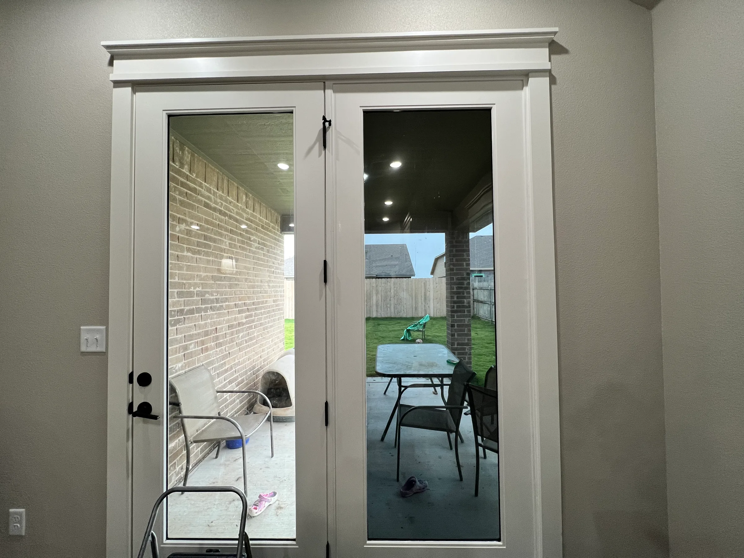 Before-and-after comparison of residential window tinting on double glass doors, showing the left door untinted with clear visibility and the right door with dark tint applied.