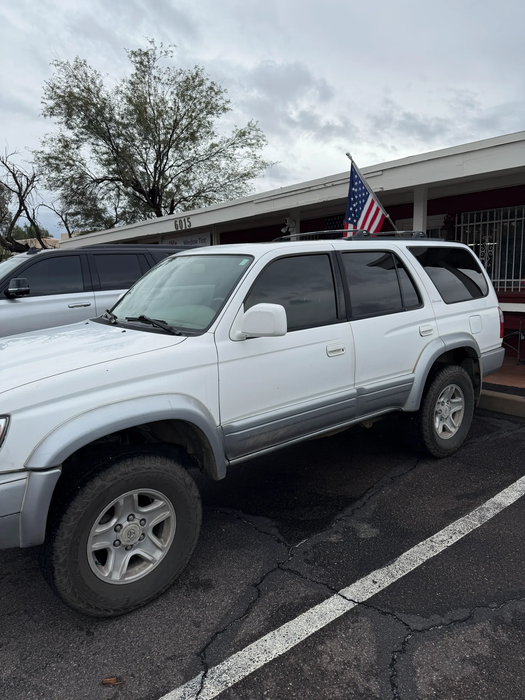 A white SUV with tinted windows parked at a storefront in Cave Creek, Arizona.